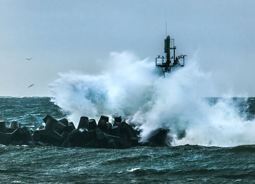 Storm wave crashing against breakwater and tower at the entrance to the port, Klaipeda, Lithuania