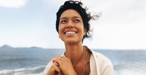 Joyful smiling woman with wavy hair enjoying a windy seaside day in close-up portrait