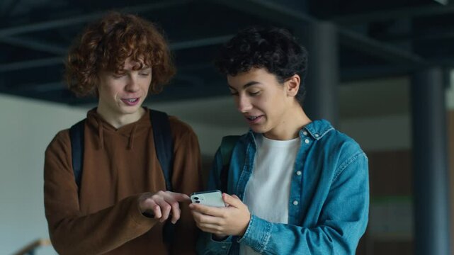 University back to school Caucasian two boys teens pupils students people guys male friends talking smiling laughing talk using mobile phone surprise shocked excited walk studying education teenagers
