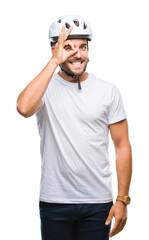 Young handsome man wearing cyclist safety helmet over isolated background doing ok gesture with hand smiling, eye looking through fingers with happy face.