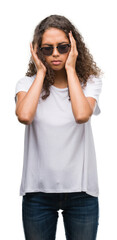 Young hispanic woman wearing sunglasses with hand on head for pain in head because stress. Suffering migraine.
