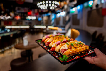 Close-up of four garnished hot dogs on a tray, with various toppings