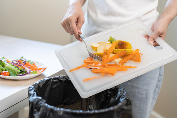 Compost from leftover food asian young housekeeper woman holding peel vegetable on cutting board...
