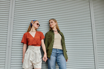 Naklejka premium A young lesbian couple shares a tender moment while strolling through a city