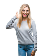 Young beautiful blonde woman wearing glasses over isolated background doing happy thumbs up gesture with hand. Approving expression looking at the camera with showing success.