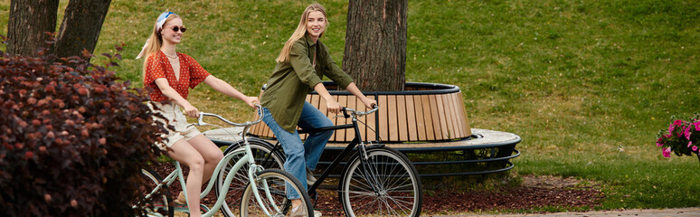 A young lesbian couple enjoys a romantic bike ride through a lush green park.