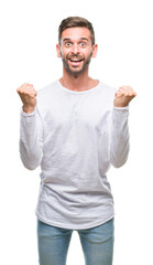 Naklejka premium Young handsome man over isolated background celebrating surprised and amazed for success with arms raised and open eyes. Winner concept.