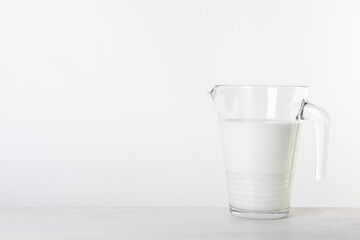 Jug of fresh milk on table against white background, space for text