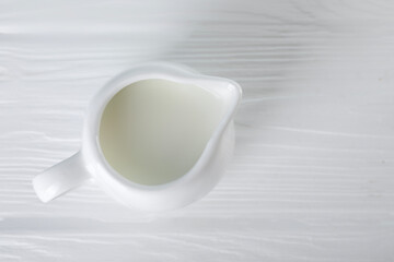 Jug of fresh milk on white wooden table, top view. Space for text