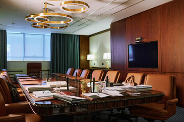 Part of spacious boardroom for working meetings of directors or lawyers with long table surrounded by several leather armchairs