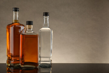 Bottles of different alcoholic drinks on table against gray background, space for text
