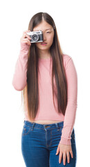 Young Chinese woman over isolated background taking pictures using vintage camera with a confident expression on smart face thinking serious