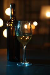 Tasty wine in glass and bottle on table against blurred lights