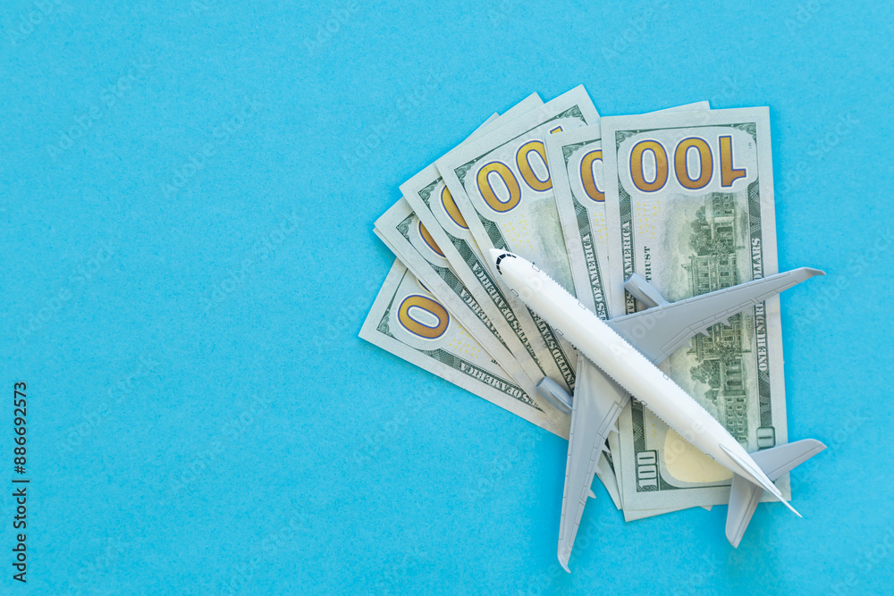 Wall mural airplane toy with money on blue background. air trip and vacation.