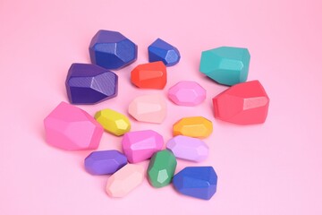 Many colorful balancing stones on pink background, above view