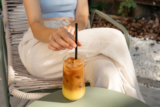 Close-up of a woman sitting in an outdoor cafe drinking an iced bumble coffee