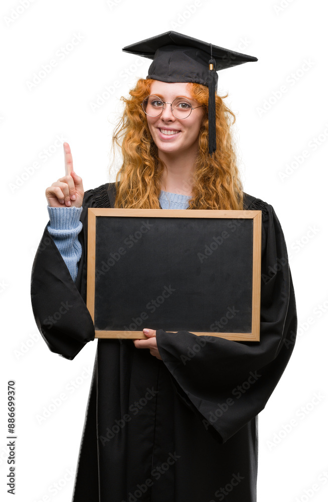 Sticker young redhead student woman wearing graduated uniform holding blackboard surprised with an idea or q