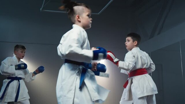 Children in karate class. Boy training martial arts. Friends training together in smoky room. Boys in white kimono training karate. They show powerful kicks. Focused males training karate. 4K, UHD