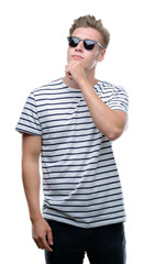 Fototapeta premium Young handsome blond man wearing sunglasess serious face thinking about question, very confused idea