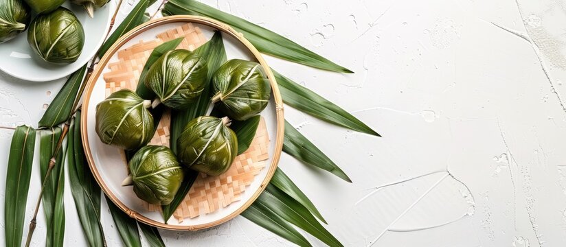 Traditional Chinese zongzies set on a plate with bamboo leaves for Dragon Boat Festival on a white background with a copy space image