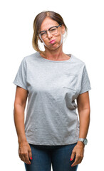 Obraz premium Middle age senior hispanic woman wearing glasses over isolated background puffing cheeks with funny face. Mouth inflated with air, crazy expression.