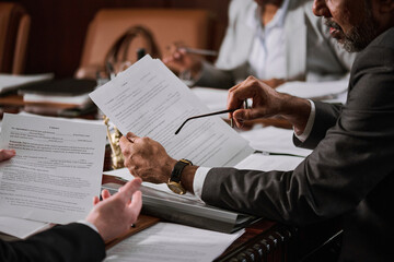 Cropped shot of mature male ceo with eyeglasses in hand holding paper document over workplace while...