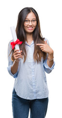 Young asian woman holding degree over isolated background with surprise face pointing finger to himself