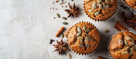 Fototapeta premium Top view of pumpkin muffins with spices and seeds on a light background offering copy space image to represent autumn Halloween and Thanksgiving baking ideas