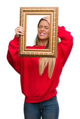 Fototapeta premium Beautiful young woman holding vintage frame stressed with hand on head, shocked with shame and surprise face, angry and frustrated. Fear and upset for mistake.