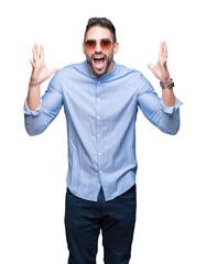 Young handsome man wearing sunglasses over isolated background celebrating crazy and amazed for success with arms raised and open eyes screaming excited. Winner concept