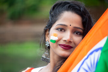 Close up of a girls face with Indian Flag painted holding indian Flag. Suitable for Independence Day or Republic Day concept.