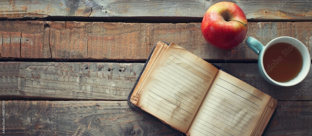Poster top down view of a wooden table adorned with an open diary featuring blank pages next to a cup of co