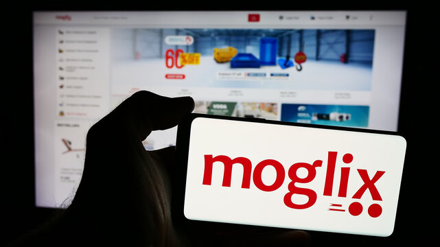 Stuttgart, Germany - 07-11-2024: Person holding smartphone with logo of e-commerce company Mogli Labs (India) Pvt. Ltd. (Moglix) in front of website. Focus on phone display.