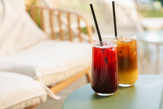 Refreshing summer drinks in tall glasses with straws on the table, on the summer terrace.