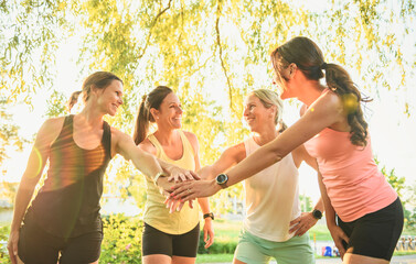females in sportswear jogging together bright sunny park in summer