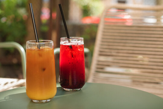 Close-up of an iced bumble coffee and fruit lemonade drink on a cafe table outdoors in summer