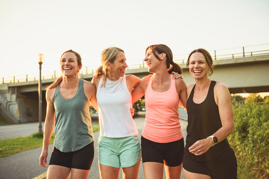females in sportswear walking together bright sunny park in summer