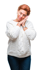 Atrractive senior caucasian redhead woman wearing winter sweater over isolated background sleeping tired dreaming and posing with hands together while smiling with closed eyes.