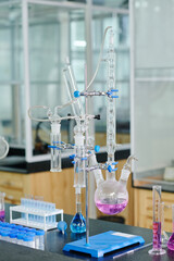 Stand with various glassware containing liquid substances on workplace of chemist or biotechnologist researching samples