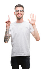 Young tattooed adult man showing and pointing up with fingers number six while smiling confident and happy.