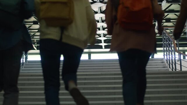 View from behind university back to school college pupils students people girls guys boys women female male men classmates friends teenagers climb up run running stairs education studying rush hurry