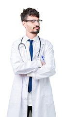 Young doctor man wearing hospital coat over isolated background smiling looking to the side with arms crossed convinced and confident