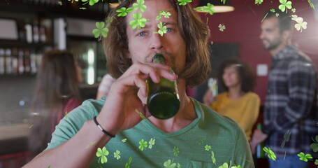 Obraz premium Image of clover icons over caucasian man drinking beer