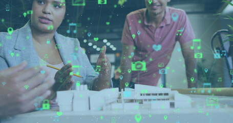 Image of network of digital icons over diverse colleagues discussing over a model at office