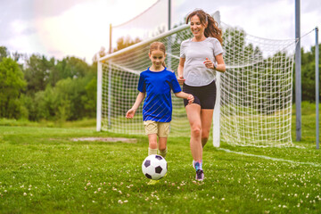 happy mother playing football outdoor on a summer day with her daughter