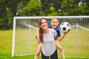 happy mother playing football outdoor on a summer day with her daughter