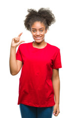 Young afro american woman over isolated background smiling and confident gesturing with hand doing size sign with fingers while looking and the camera. Measure concept.