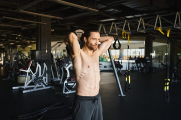 A muscular man with no shirt on is working out in a gym.