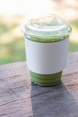 Iced matcha green tea with milk on wooden table with nature bokeh background.