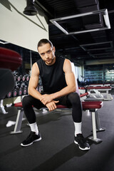 An athletic man in workout gear sitting on a gym bench, taking a break from his vigorous training routine.